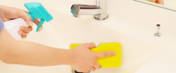 洗面台を洗剤とスポンジで磨いている手元