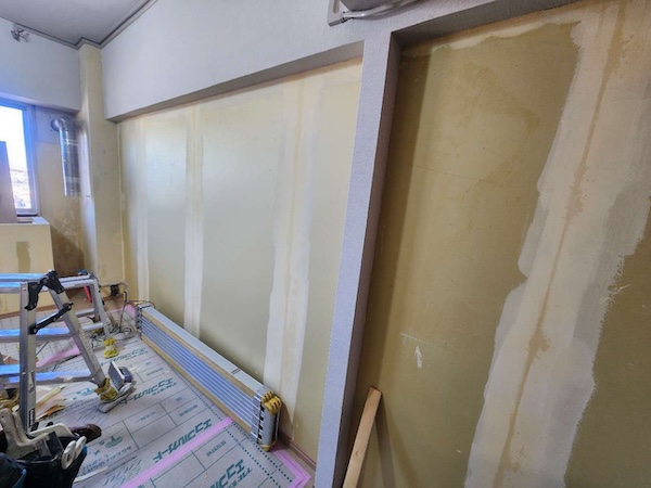 床を養生して壁の下地処理を進めているマンションの室内